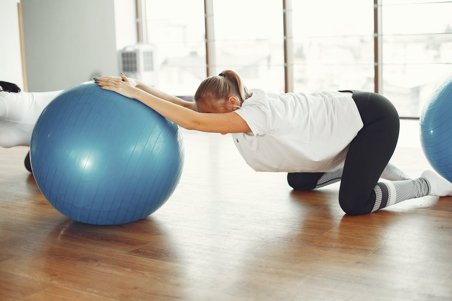 young pregnant woman doing stretching exercise with fit ball